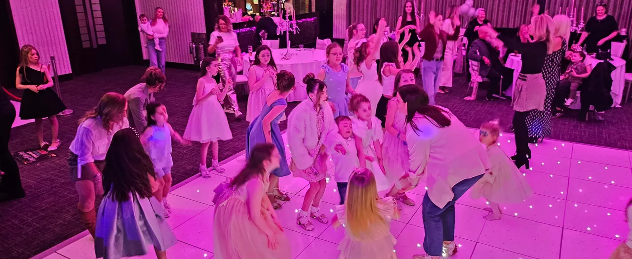 A busy LED dance floor with children and adults dancing together at a formal family party