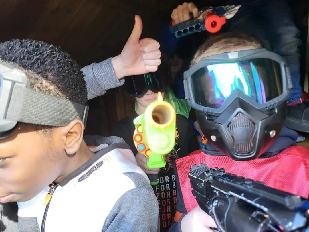 Close-up of two boys wearing protective face masks and goggles, one giving a thumbs up mid-game
