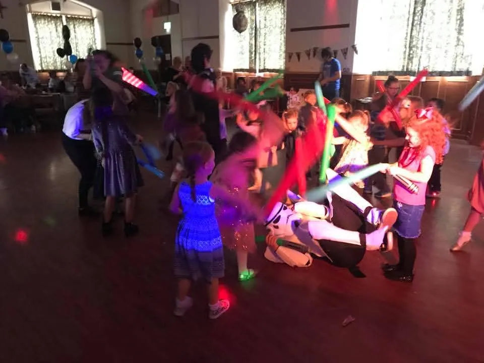 Children dancing with light-up foam sticks on the dance floor at a kids disco