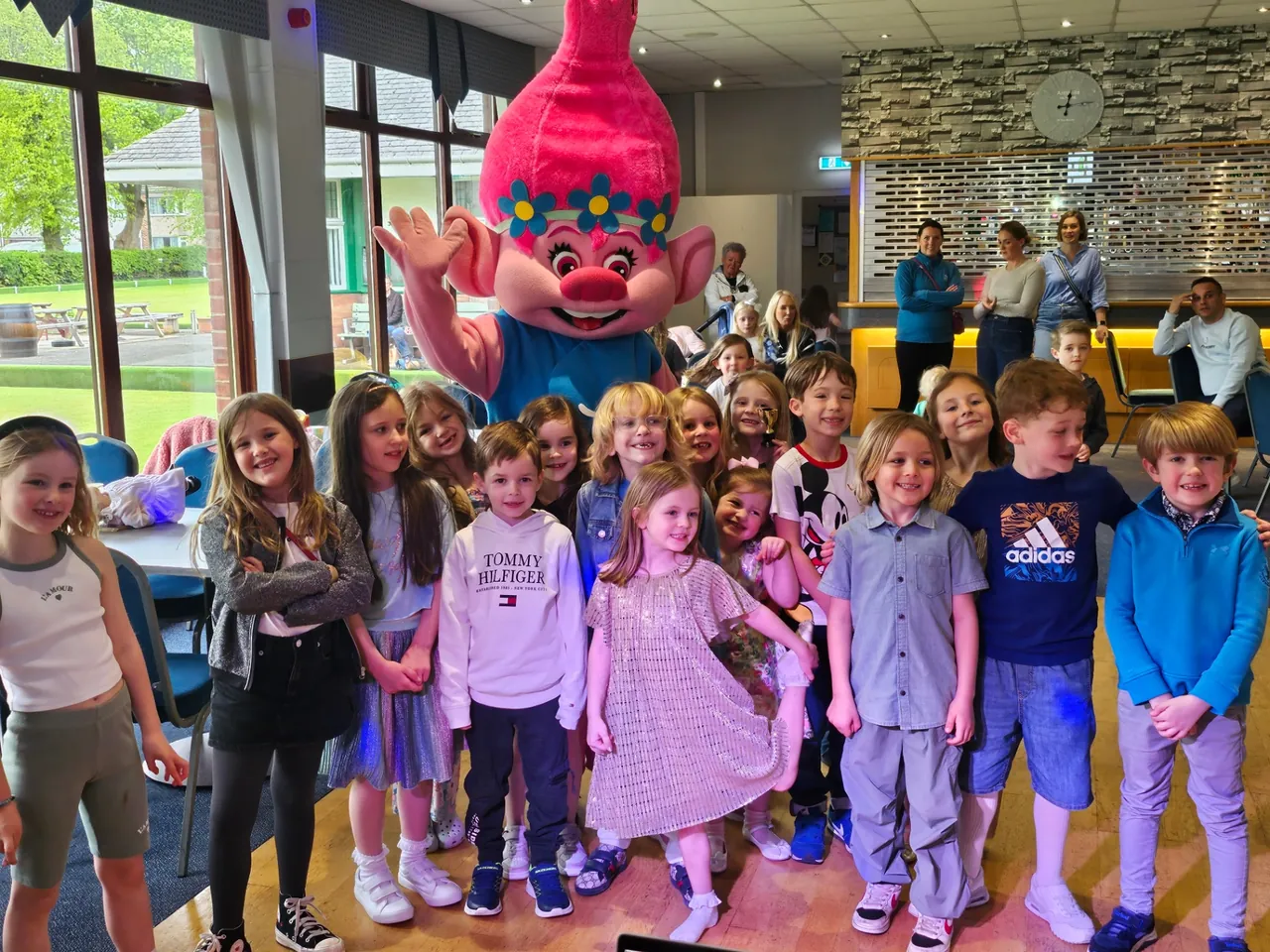 A group of children posing together with a costume character in a bright party venue