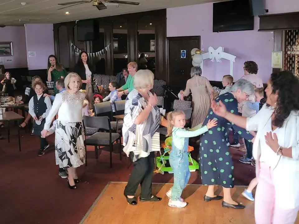 Children, parents and grandparents dancing together at a family celebration in a Glasgow function suite